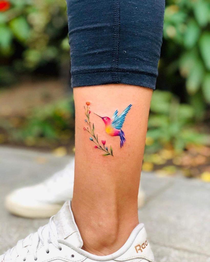 1 TOP 1 tatouages de colibris colorés sur le mollet avec de petites fleurs et des couleurs jaune fuchsia bleu clair vert rouge violet