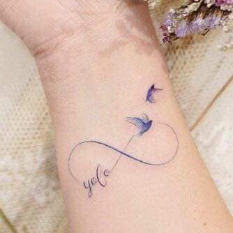 4 TOP 4 Delicate Small Infinity Tattoo dans des tons bleutés avec deux oiseaux, un prenant son envol, un fils et un nom au poignet