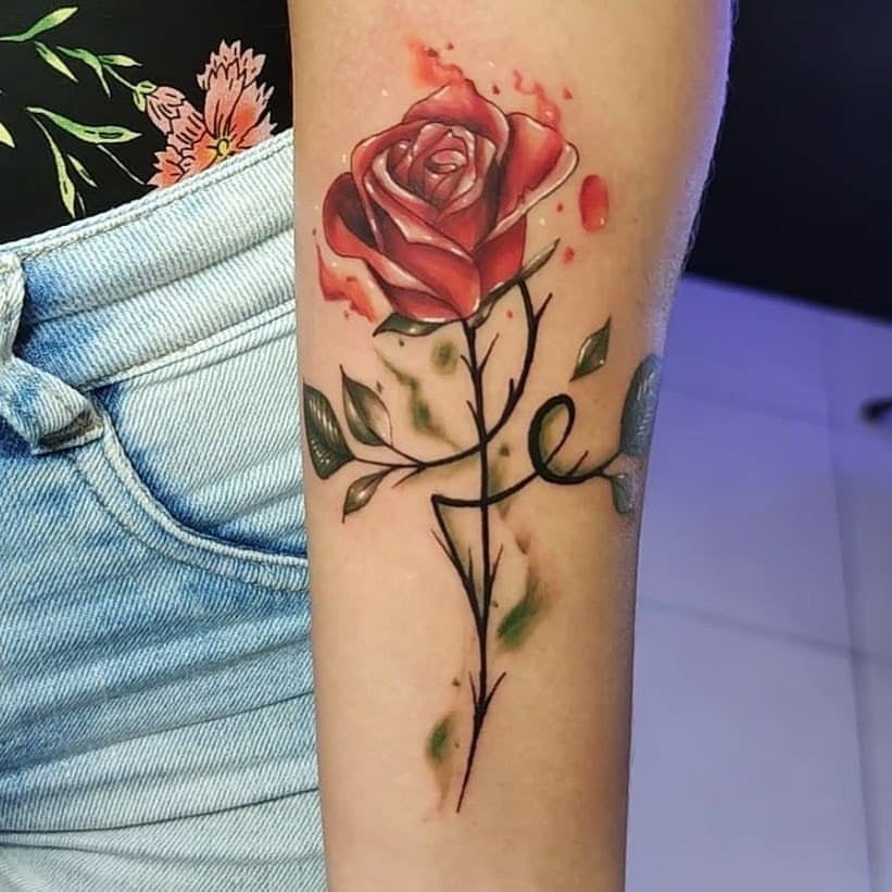 Tatuajes de Rosas Con tallo con espinas formando la palabra Fe Rojo y acuarela verde en antebrazo