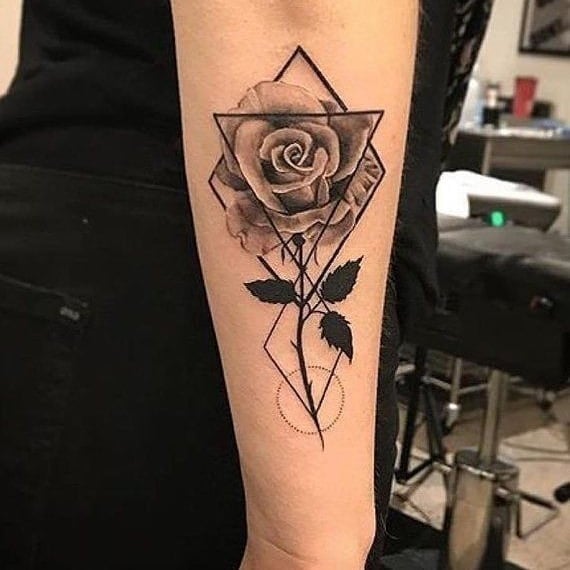 Tatouages de roses inscrites dans des triangles et des losanges sur le fond géométrique de l'avant-bras