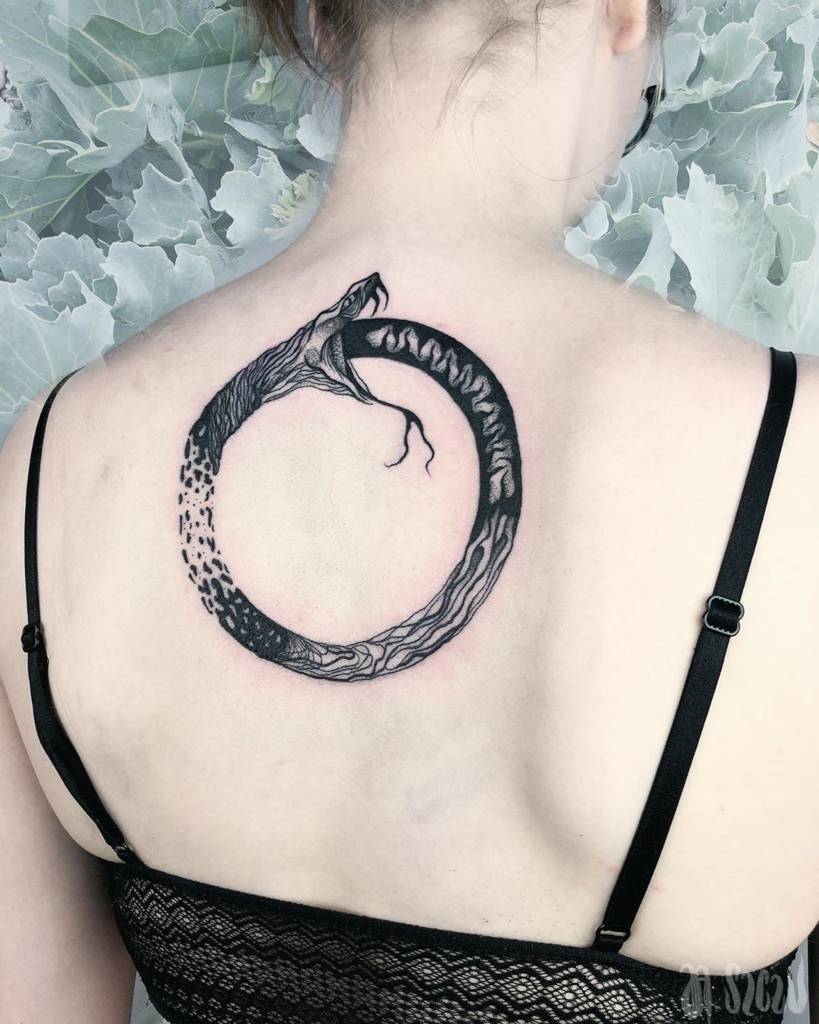 Tatuaggi runici nordici celtici vichinghi Ouroboros o serpente uroboros che si mangia la coda sulla schiena di una donna nera