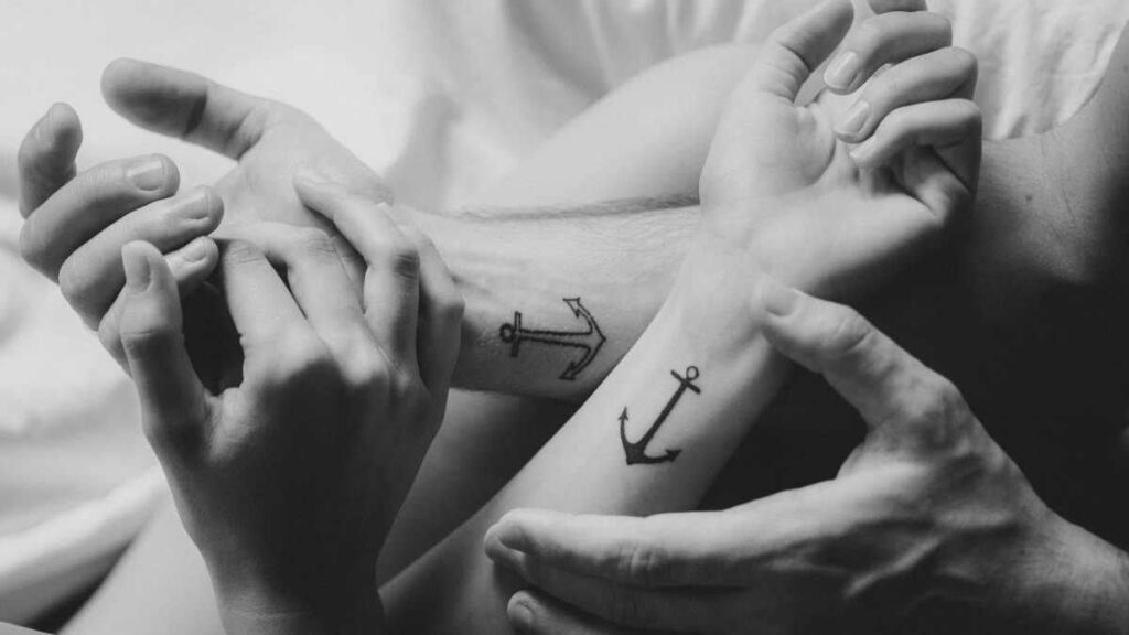 Tatuagens pequenas e complementares para casais nos pulsos Âncoras uma preenchida e outra não