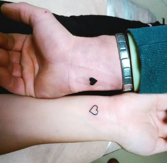 Piccoli tatuaggi complementari per coppie sui polsi: cuore pieno e cuore vuoto