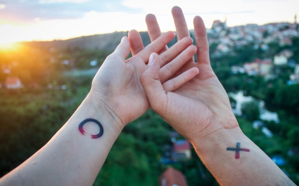 Kleine und komplementäre Tattoos für Paare an den Handgelenken Kreuz und Kreis in Verlaufsfarben