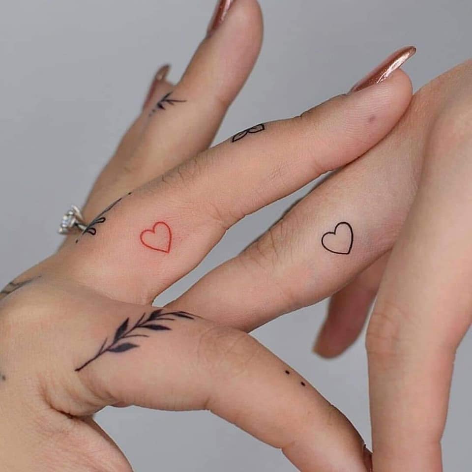 39 Tattoos on the Fingers for Couples or Friends Outline of small hearts one red another black on older fingers