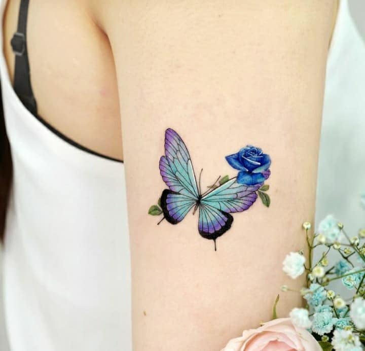 Tatuagem de borboleta no braço com rosa azul
