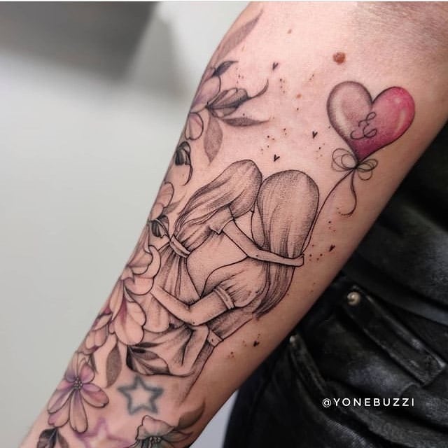 Tatuaggi sull'avambraccio per madri e figlie Bellissimo motivo di una madre che tiene in braccio la figlia con un palloncino a forma di cuore e fiori