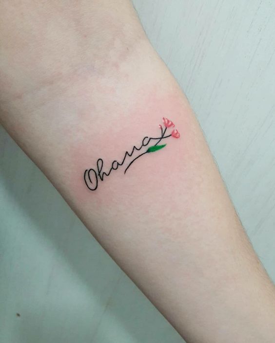 14 tatuaggi con frasi di famiglia Ohana con piccoli fiori di rosa e ramo verde sull'avambraccio
