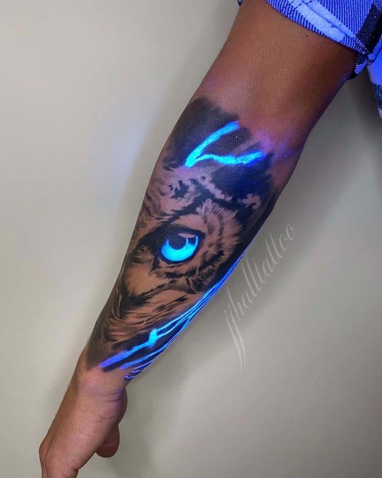 49 tatouages à l'encre UV sur la moitié du visage d'un hibou luminescent sur l'avant-bras