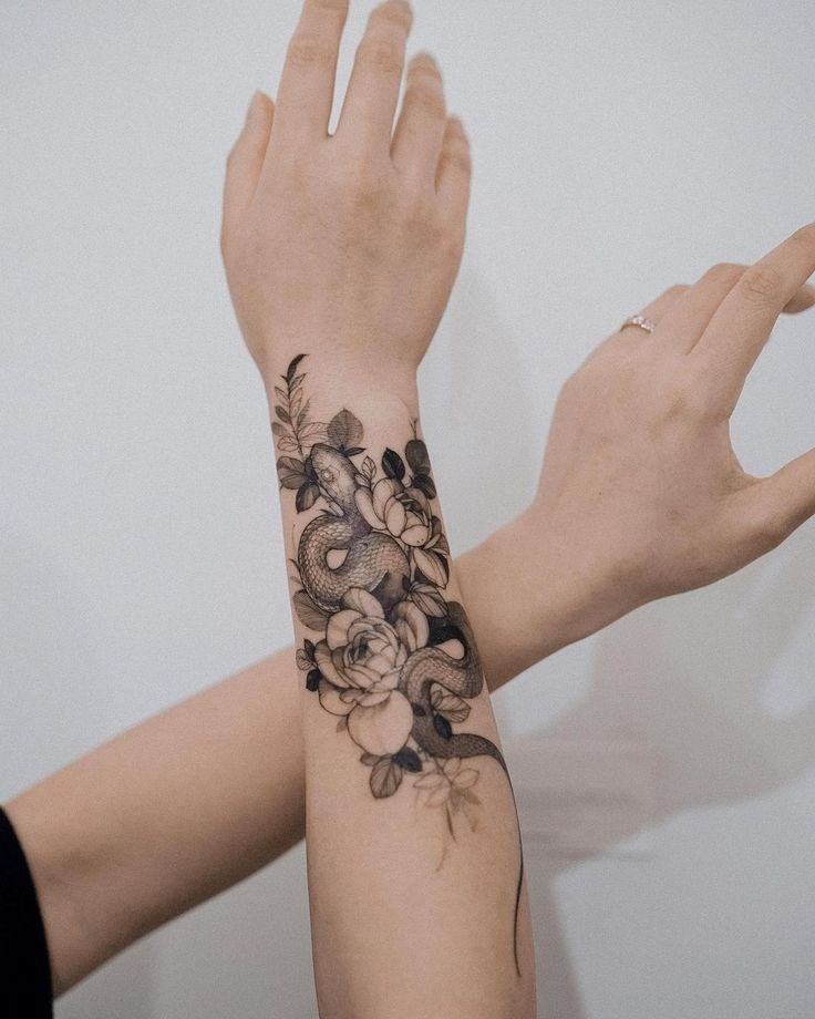 5 tatuaggi serpente sull'avambraccio con motivi naturali, foglie e fiori in nero 1