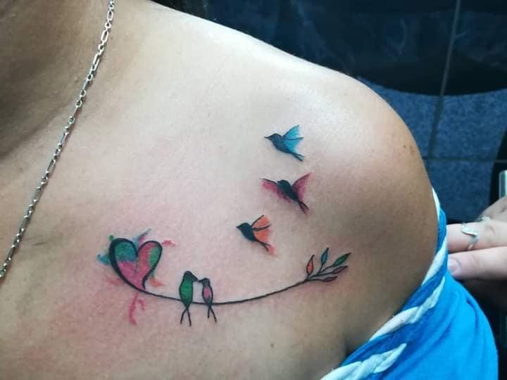 7 Tattoos von Vögeln und Farben auf dem Schlüsselbein, ein Paar Herzvögel und drei Kindervögel in farbigem Aquarell