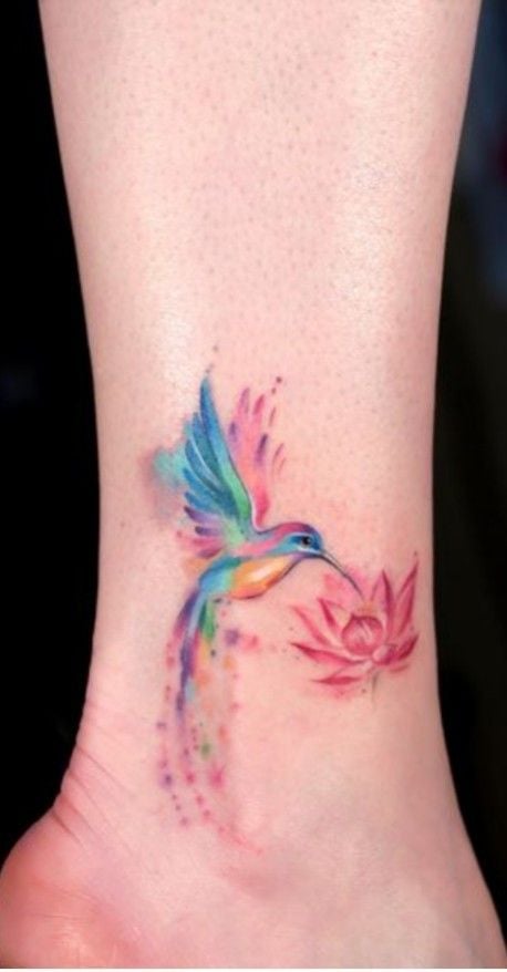 8 tatuagens de pássaros e cores beija-flor com asas azuis e rosa picando flor de lótus rosa na panturrilha