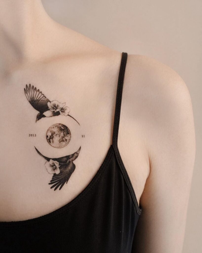 82 Tattoos für Frauen Schöne zwei Vögel, die einen Kreis bilden, in dessen Mitte sich ein Planet oder Mond befindet, ebenfalls Jahreszahlen 2013 13 in Schwarz auf dem Schlüsselbein