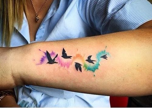 9 Tatuaggi di Uccelli e Colori sul lato dell'avambraccio in acquerello quattro uccelli neri che rappresentano la famiglia