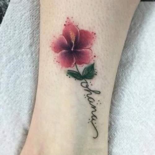 Flor vermelha da família Ohana e tatuagem de folhas verdes na panturrilha