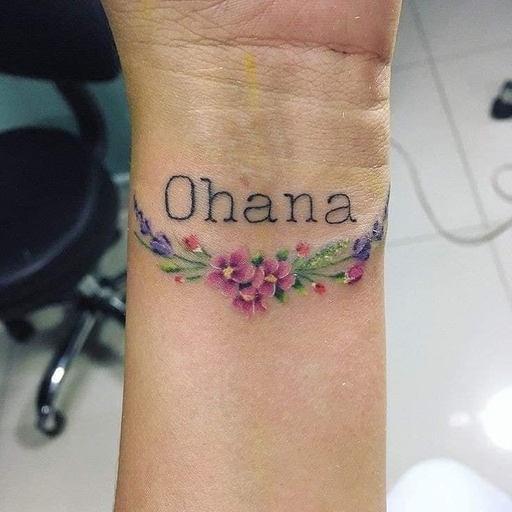 Tatouage Ohana Family belle lettre au poignet avec des lauriers de fleurs violettes roses et de brindilles