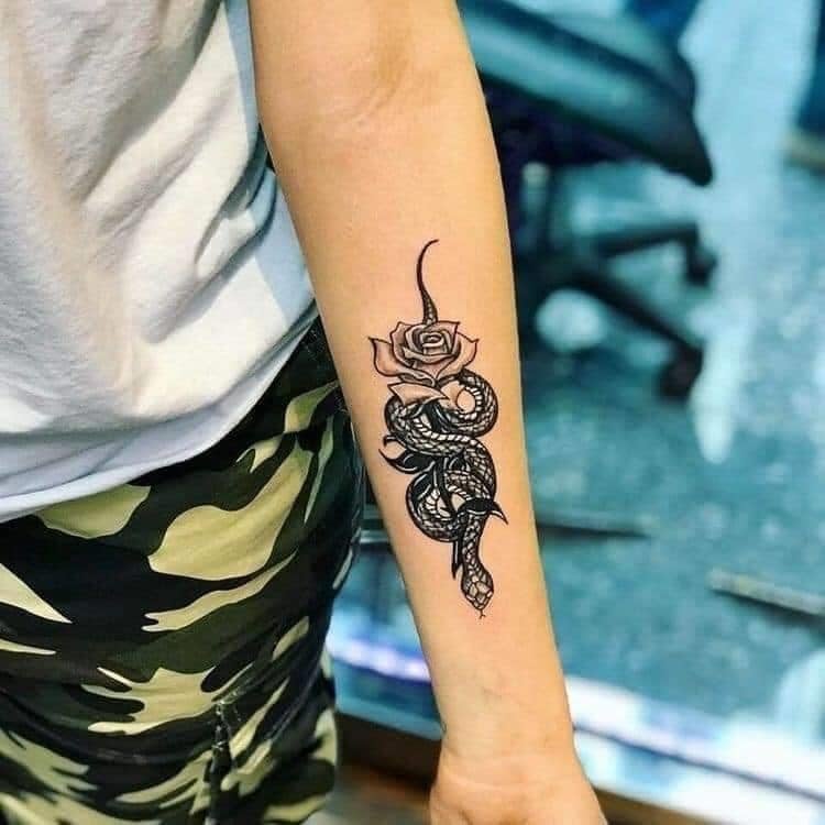 Tätowierungen einer Frau mit lebhaften Schlangen auf dem Unterarm mit einer Rose
