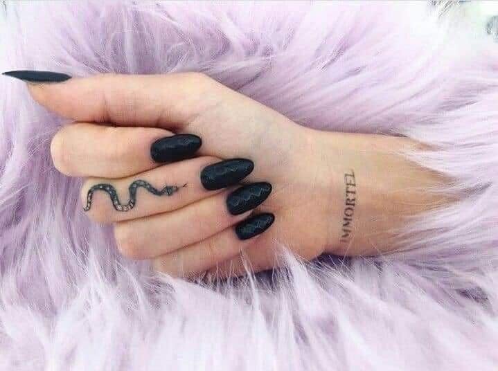 Tätowierungen einer Frau mit lebhaften Schlangen auf dem Finger der Hand