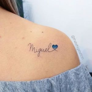 Tatuaggi con il vero nome di Miguel in corsivo con un cuore blu sulla spalla
