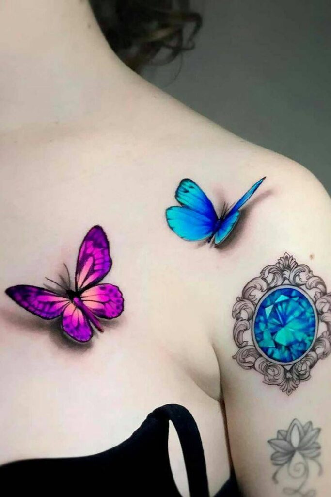 22 tatouages de papillons 3D fuchsia sur la clavicule et céleste sur l'épaule avec une gemme émeraude bleue sur le bras