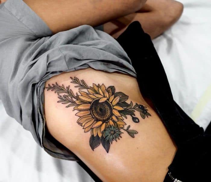 42 Tatuagens de Girassol nas Costelas na lateral do peito grande com folhas e galhos