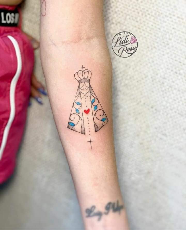5 Really Beautiful Tattoos Women Virgin Mary with a mantle with a touch of light blue color and a red heart with a crown cross on a forearm