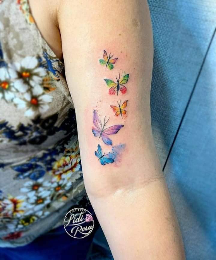 6 Tatuajes Realmente Bellos Mujeres Cinco Mariposas de diferentes Colores verdes y rojas azules y violetas en brazo Acuarelado