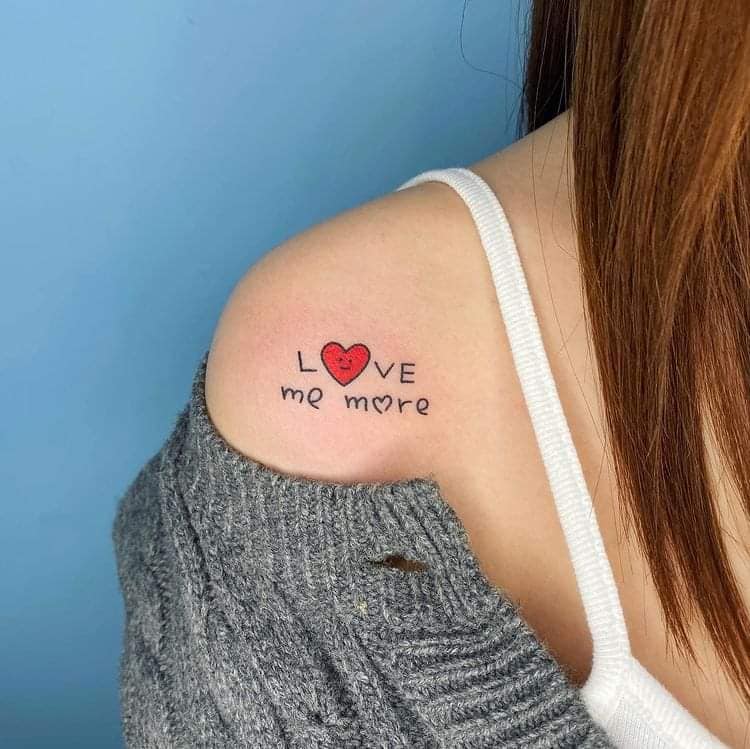 78 petits tatouages de couleur sur l'épaule avec la phrase love me more et le coeur rouge