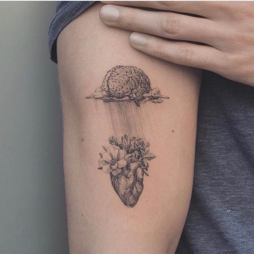 Tatuajes de Corazones Dibujo Donde se ve un corazon real con adorno de flores arriba y mas arriba un cerebro tambien tipo realista en brazo