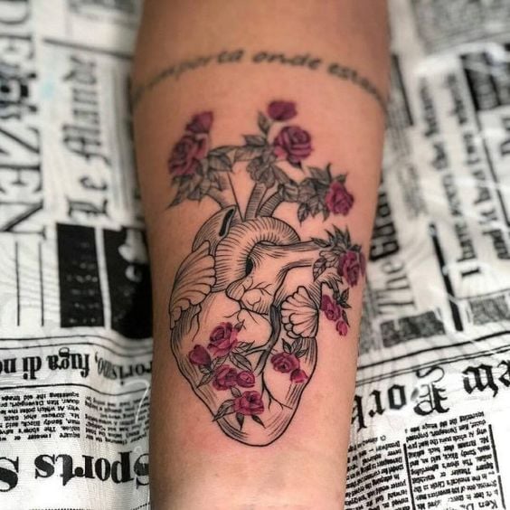 Tatuaggi a forma di cuore sull'avambraccio, cuore con arterie e vene e fiori di rosa rossa che ne escono