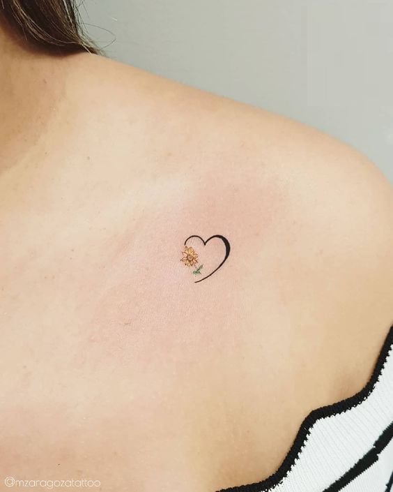 Piccoli tatuaggi minimalisti a forma di cuore sulla clavicola con girasole
