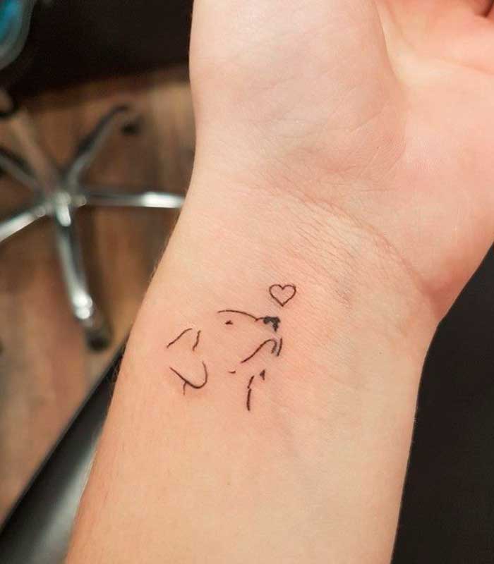 Tatuagens de cachorro de contorno pequeno no pulso olhando para um coração