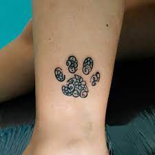 Tatuaggi per cani impronta di cane sul polpaccio decorata all'interno con motivi a spirale