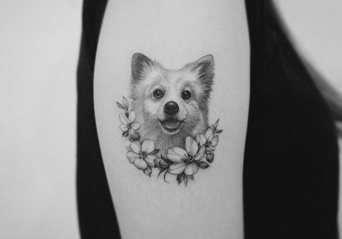 Tatouages de chien portrait réaliste sur le bras avec des fleurs blanches ci-dessous