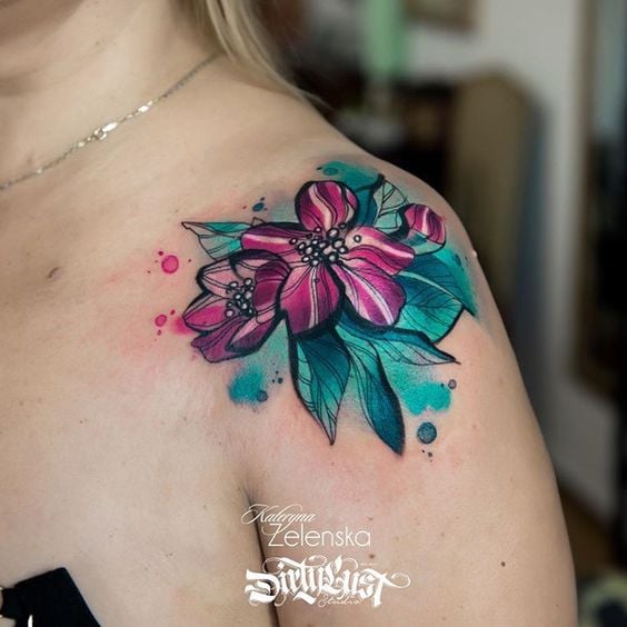 Tatuaggi di fiori di petunia viola acquerello su foglie azzurre sulla spalla