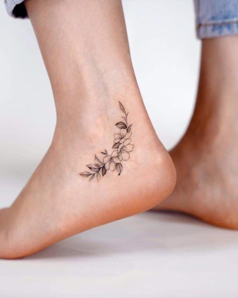 11 tatuagens nos tornozelos perto do calcanhar três flores com um ramo de folhas