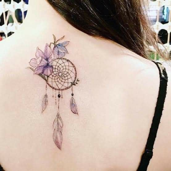 13 Dreamcatcher tattoos on the back below the neck with violet and blue flowers and feathers
