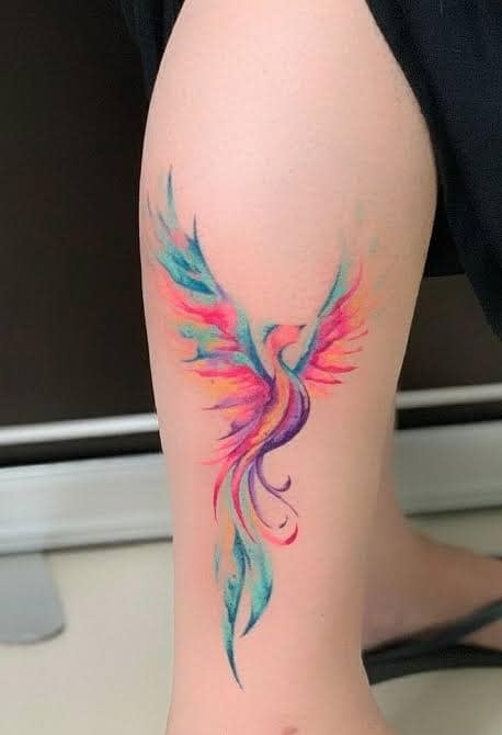 18 Tatuaje de Ave Fenix en pierna colores acuarelados cian bordo violeta