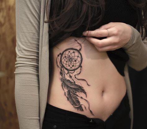 8 tatouages de plumes sur l'abdomen avec un attrape-rêves noir