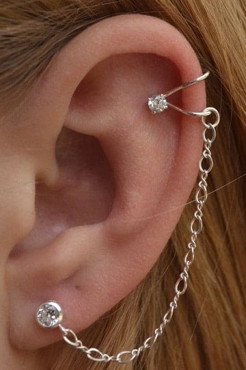 113 Piercings in the Ear lobe opener with brilliant stone connected by silver chain to the upper part