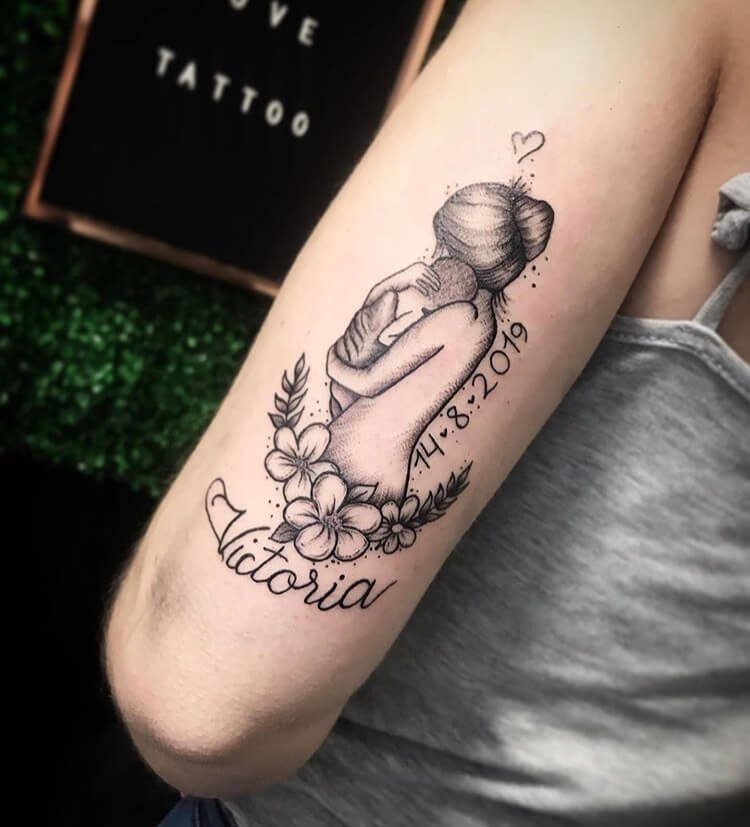 42 Tatuaggi della madre per bambini sul braccio della madre che tiene la piccola Victoria
