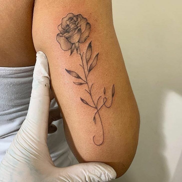 Tatuaje de Rosa negra con la palabra Fe en la parte de atras del brazo