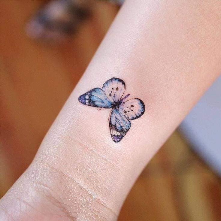 Petits et délicats tatouages de papillons bleu ciel sur le poignet