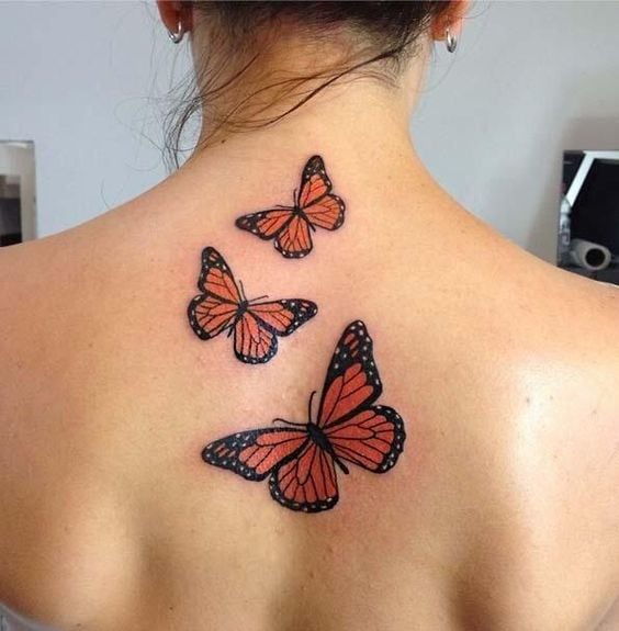 226 Tatuaggi sulla schiena Tre farfalle imperatori arancioni di diverse dimensioni alla base del collo