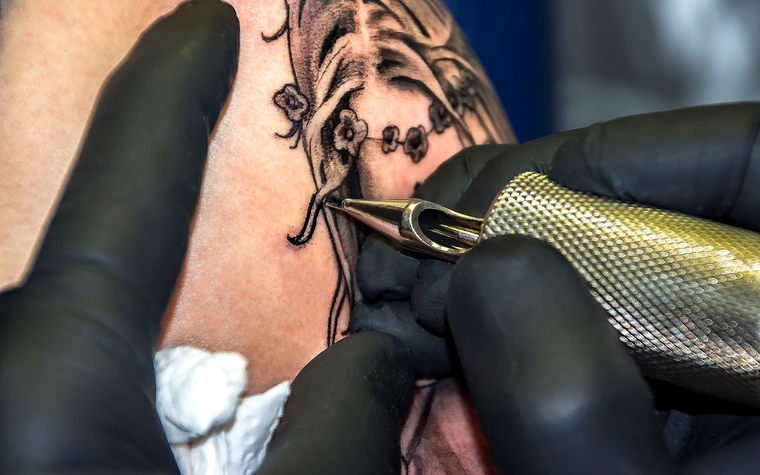 5 Ejemplo de Tatuador realizando tatuaje con maquina