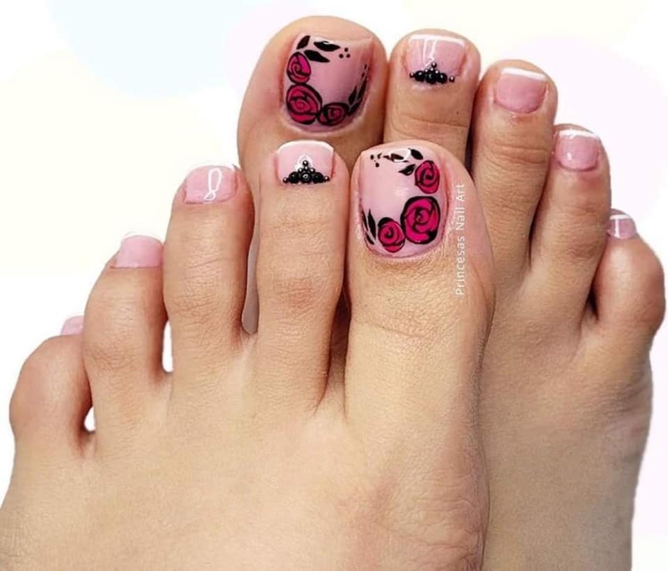Unghie dei piedi dipinte di rosa con fiori rossi sull'alluce e decorazioni con palline nere