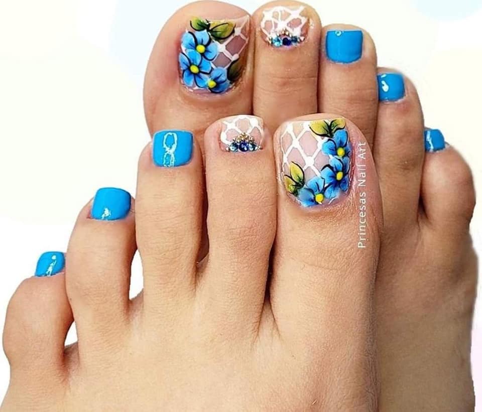 Unghie dei piedi dipinte in azzurro tranne due dita in rosa con fiori blu