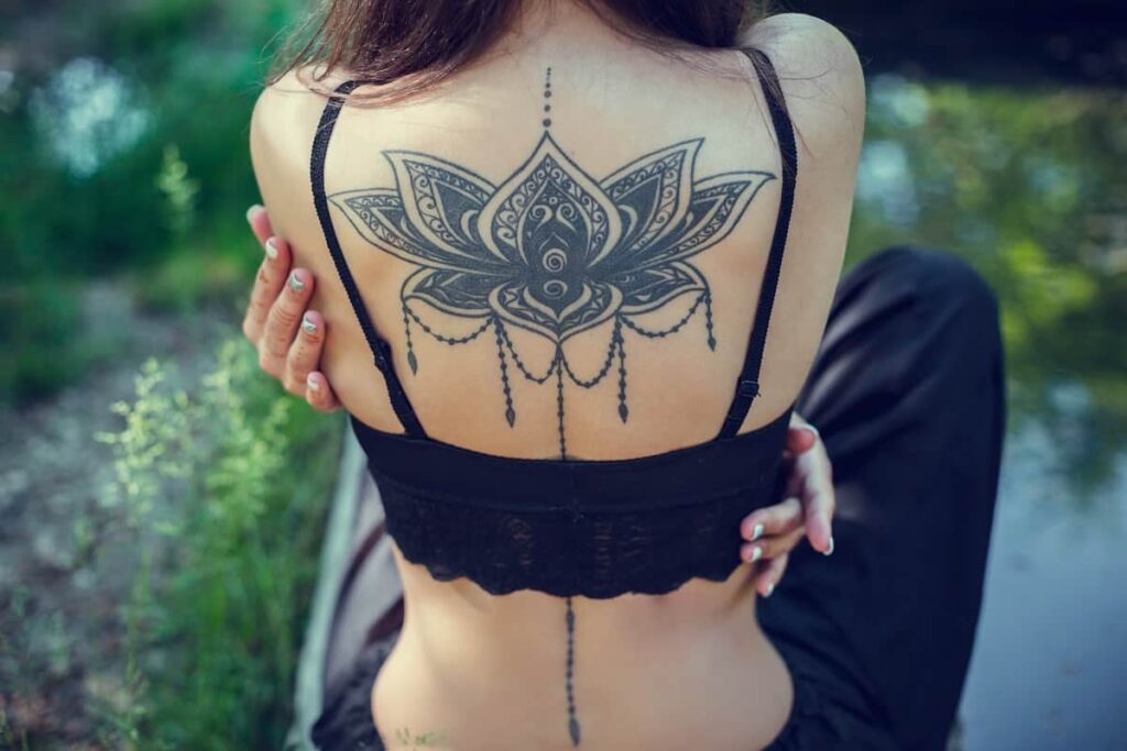 Tatuajes Espalda Mujer Hermosos Gran flor de Loto Negra con cadeita a lo largo de la columna