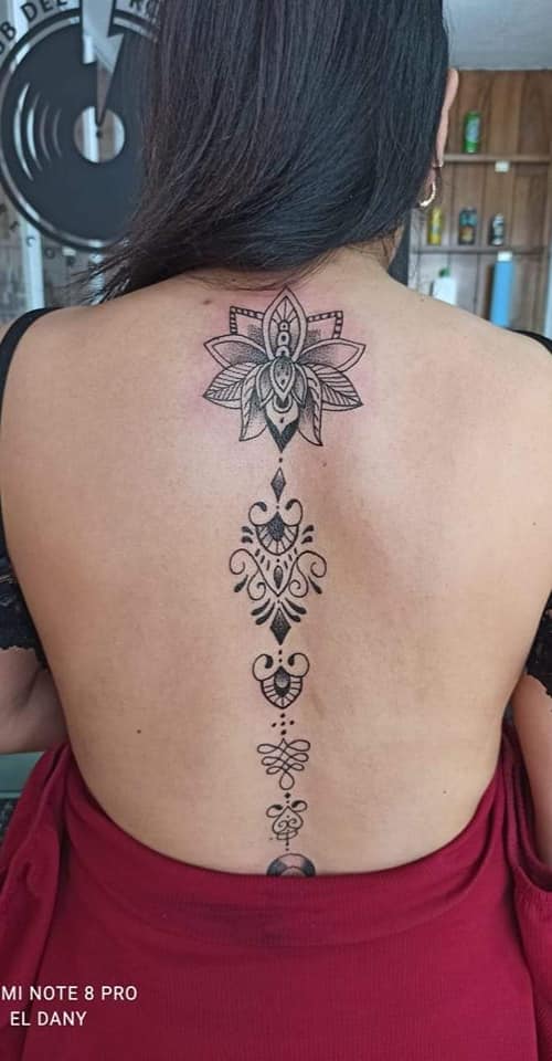 Most liked Women's tattoos Unalome lotus flower along the spine on the back