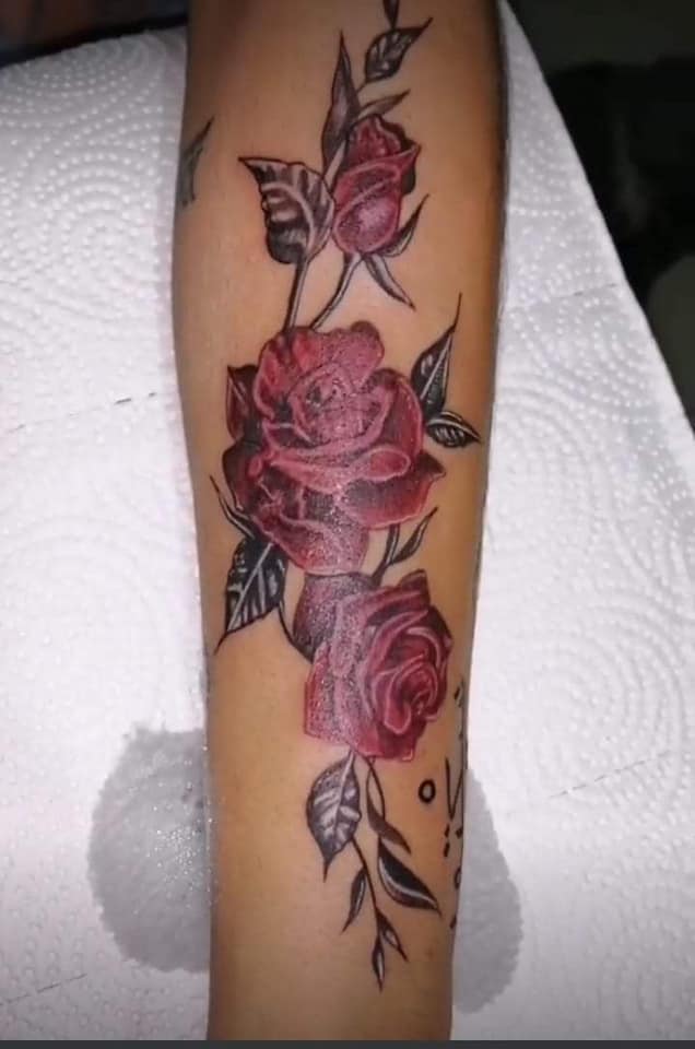 I tatuaggi femminili più apprezzati sono tre grandi rose rosse sull'avambraccio
